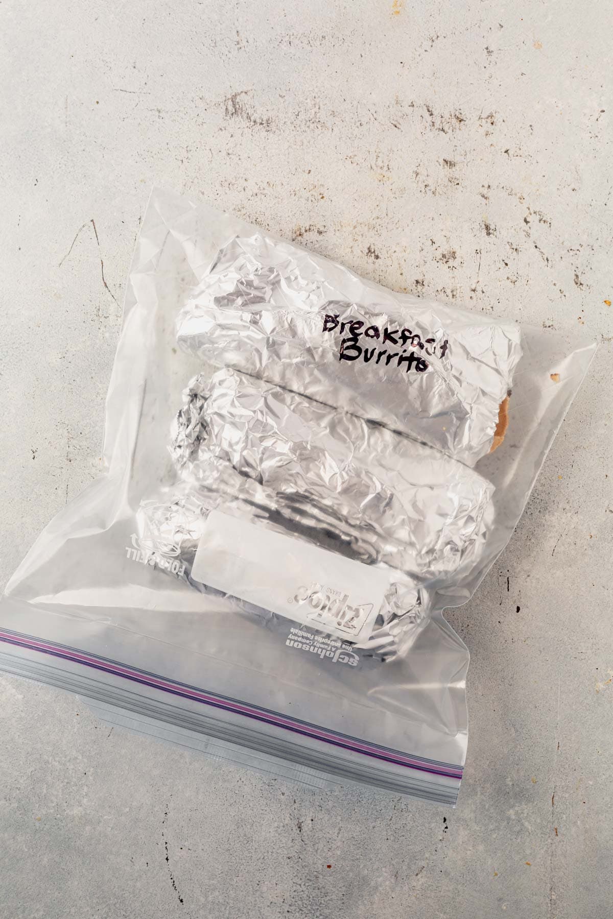 high protein breakfast burritos wrapped in foil and stored in a freezer safe bag.