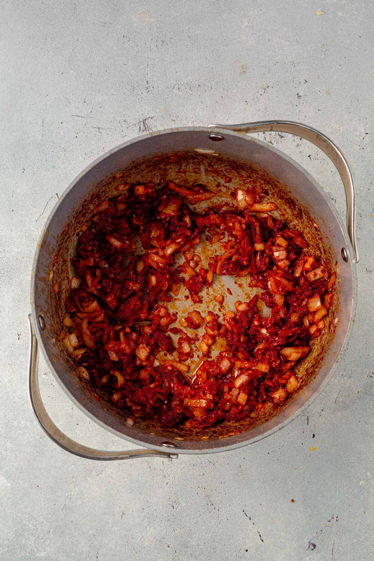 onion, tomato paste, and garlic cooked in a soup pot.