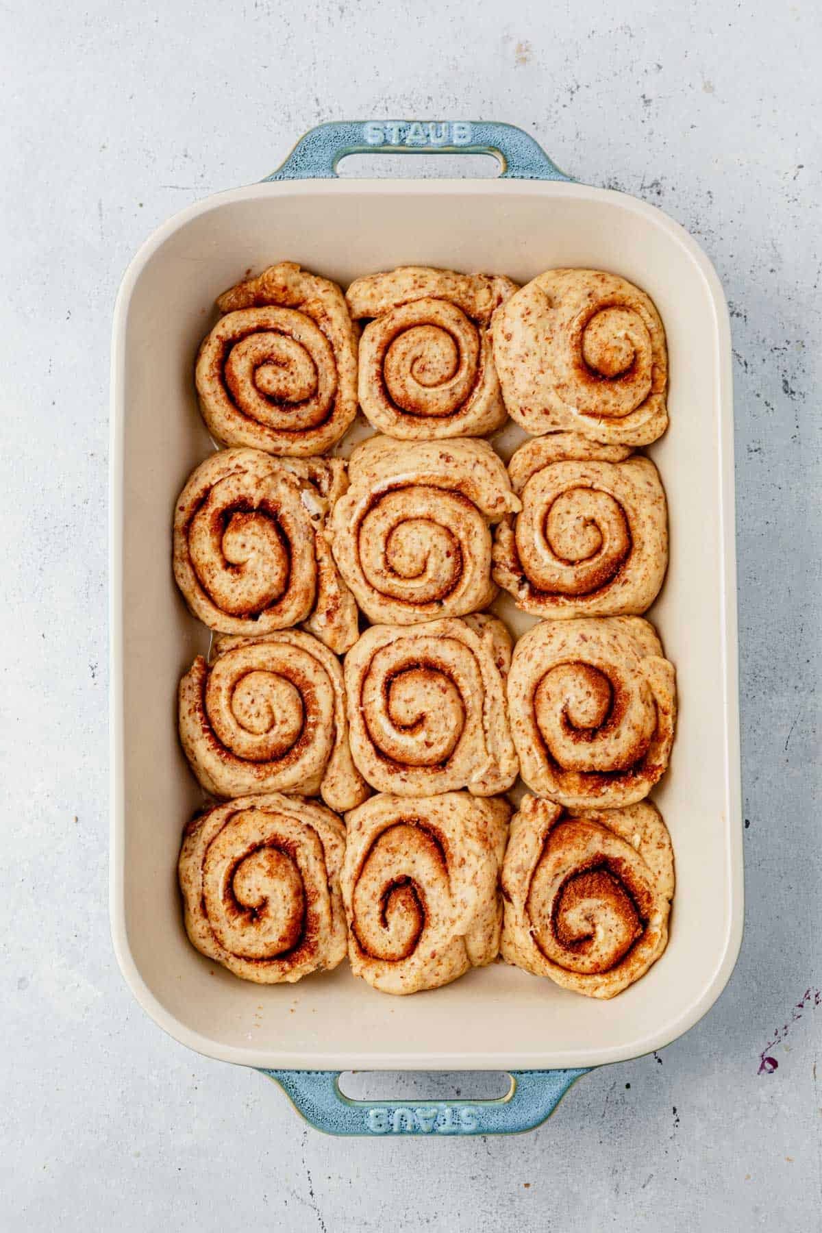 unabaked cinnamon rolls in a casserole dish after rising and doubling in size.