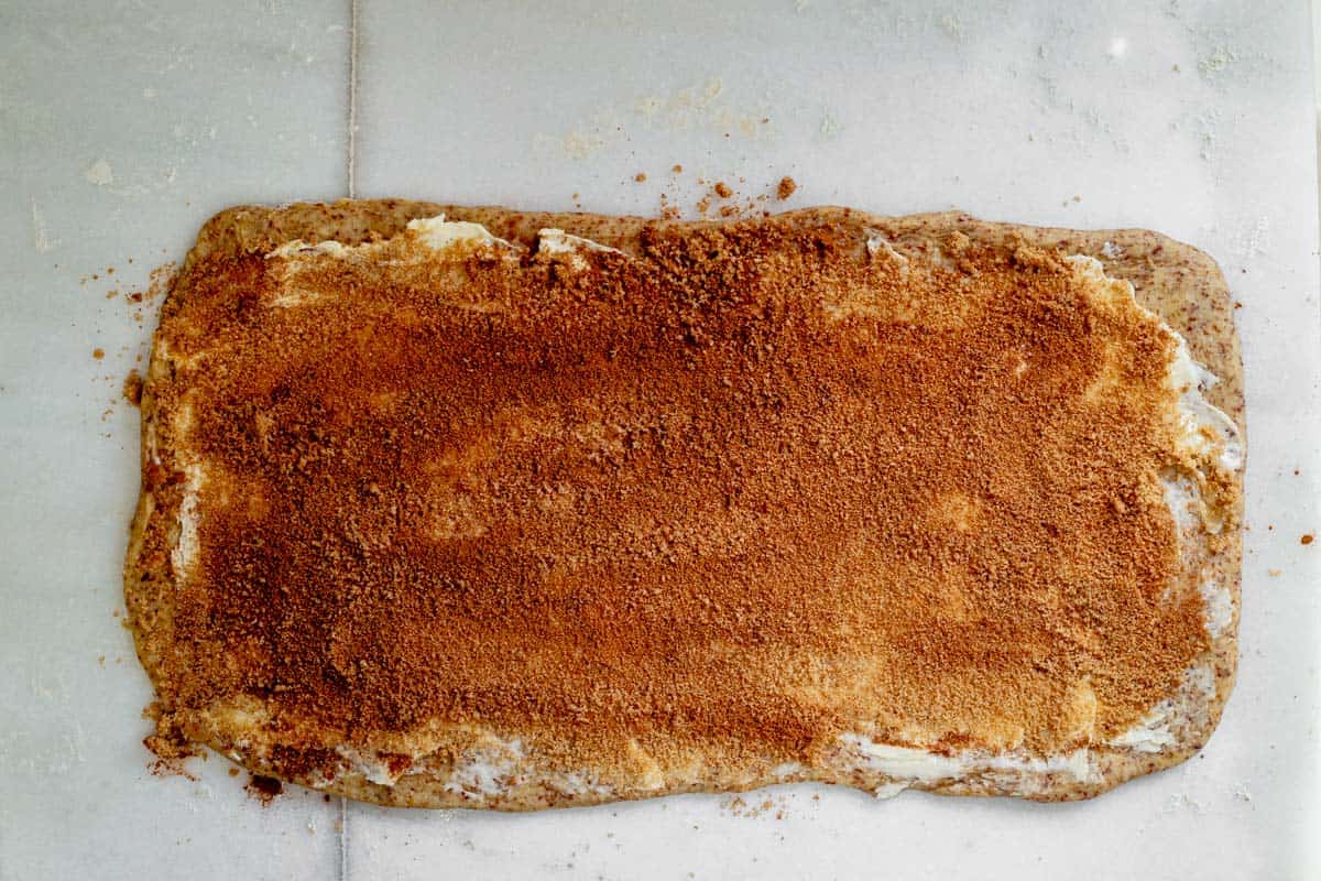 cinnamon roll dough rolled in a rectangle with butter, sugar, and cinnamon spread on top.