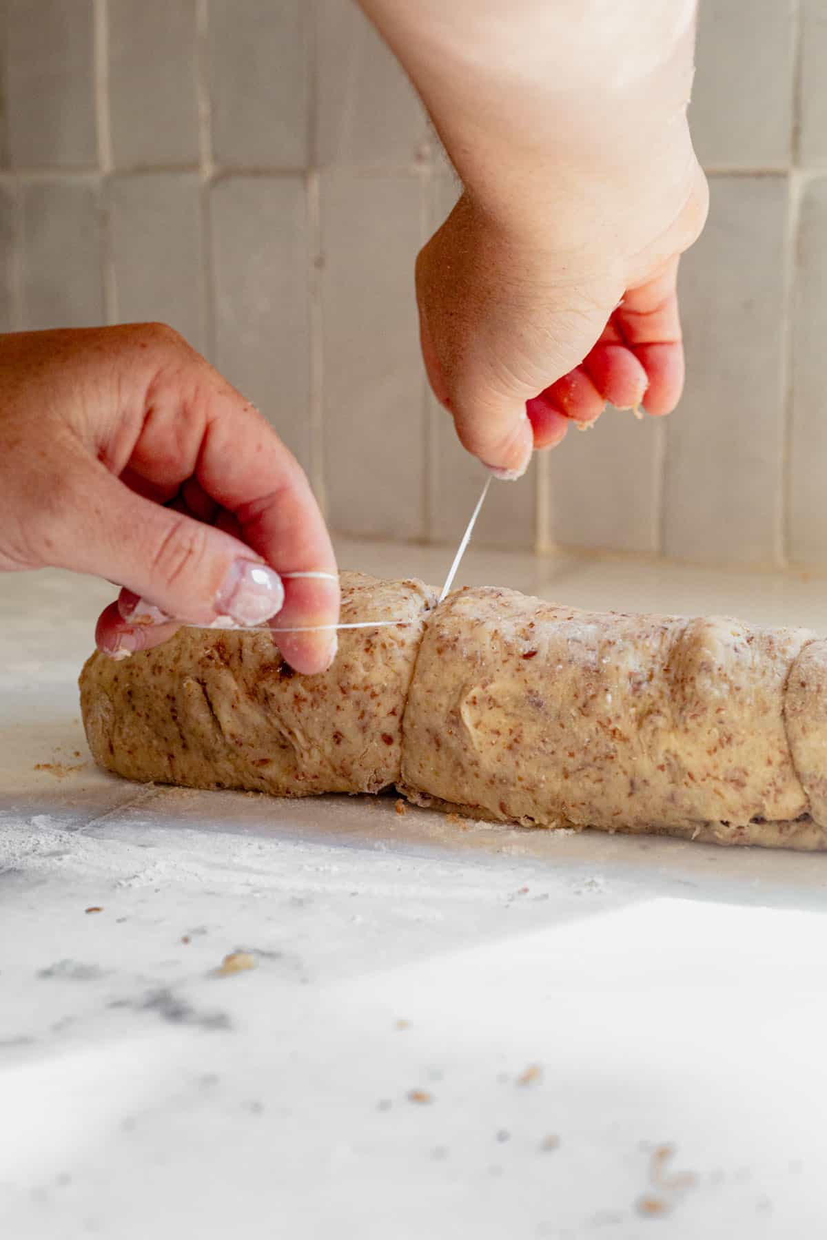 cutting cinnamon roll dough with dental floss.