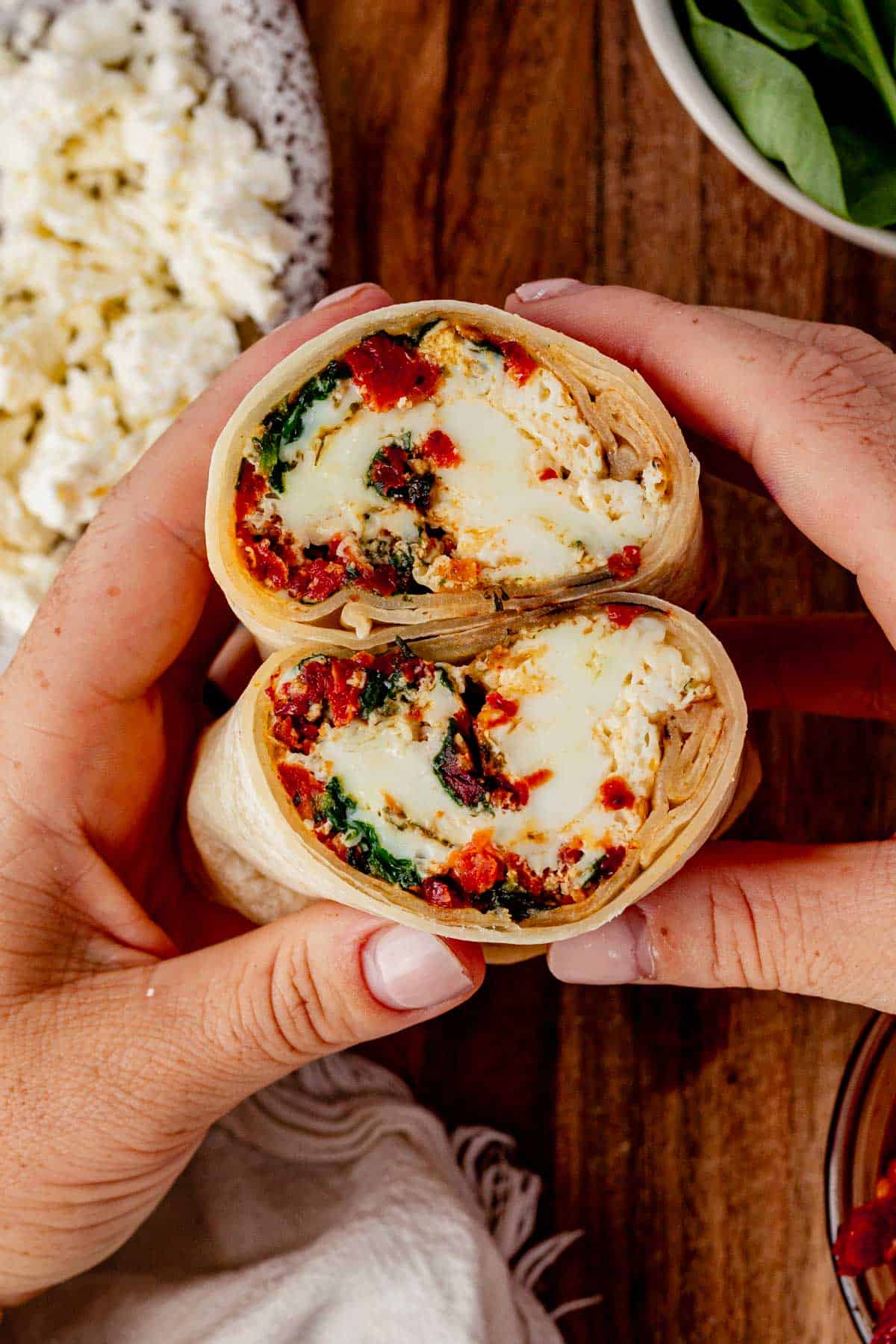 holding two halves of a spinach feta egg what wrap.