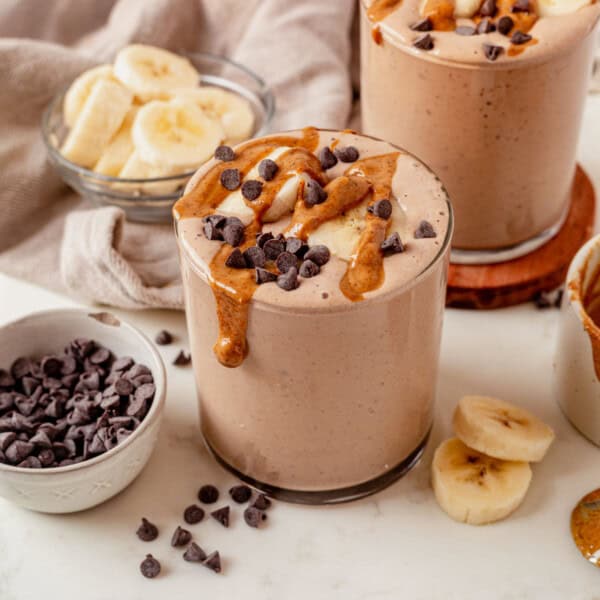 chocolate peanut butter protein smoothie on a countertop with peanut butter and chocolate chips on top.