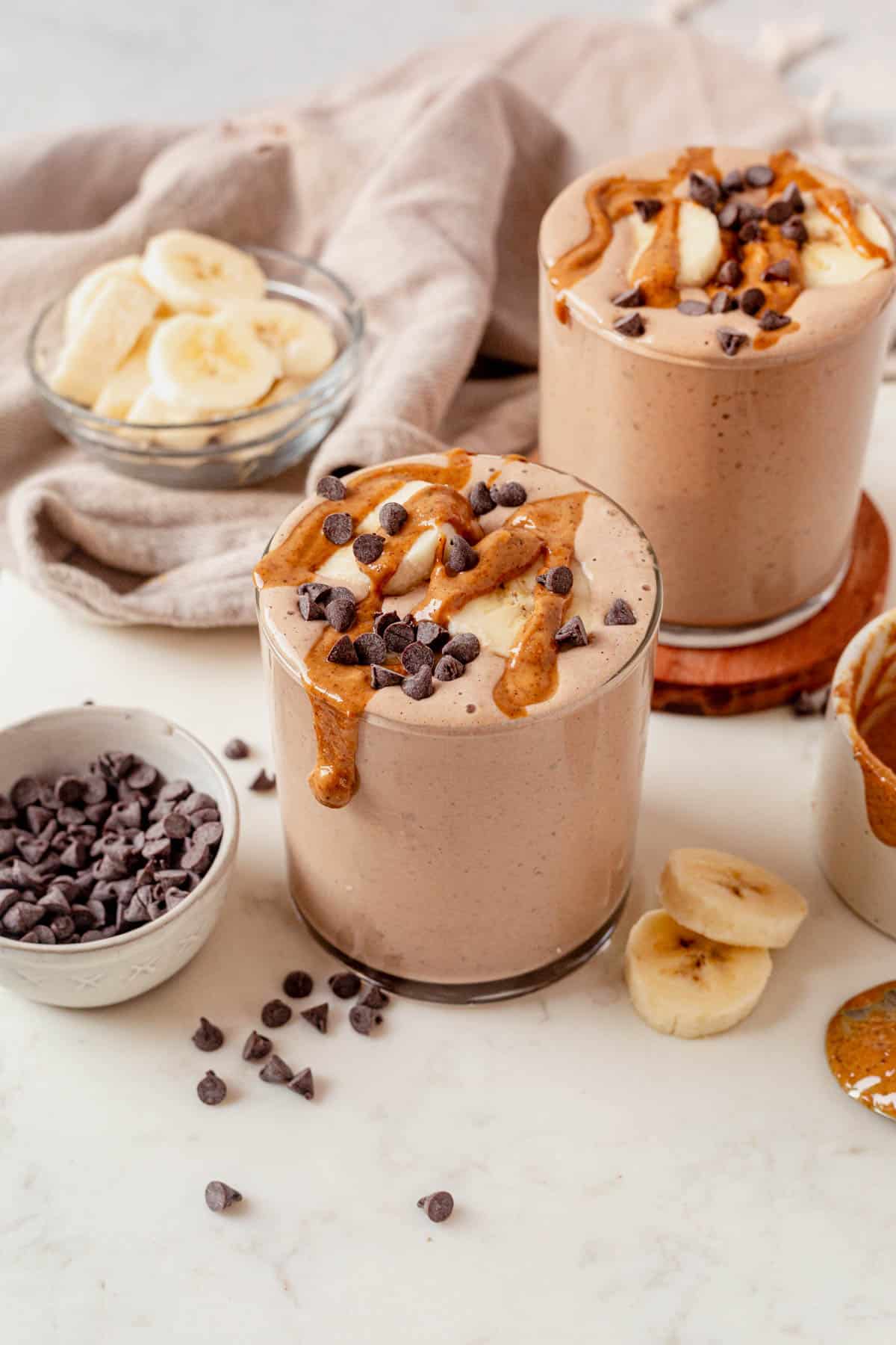 two chocolate peanut butter protein smoothies on a countertop.