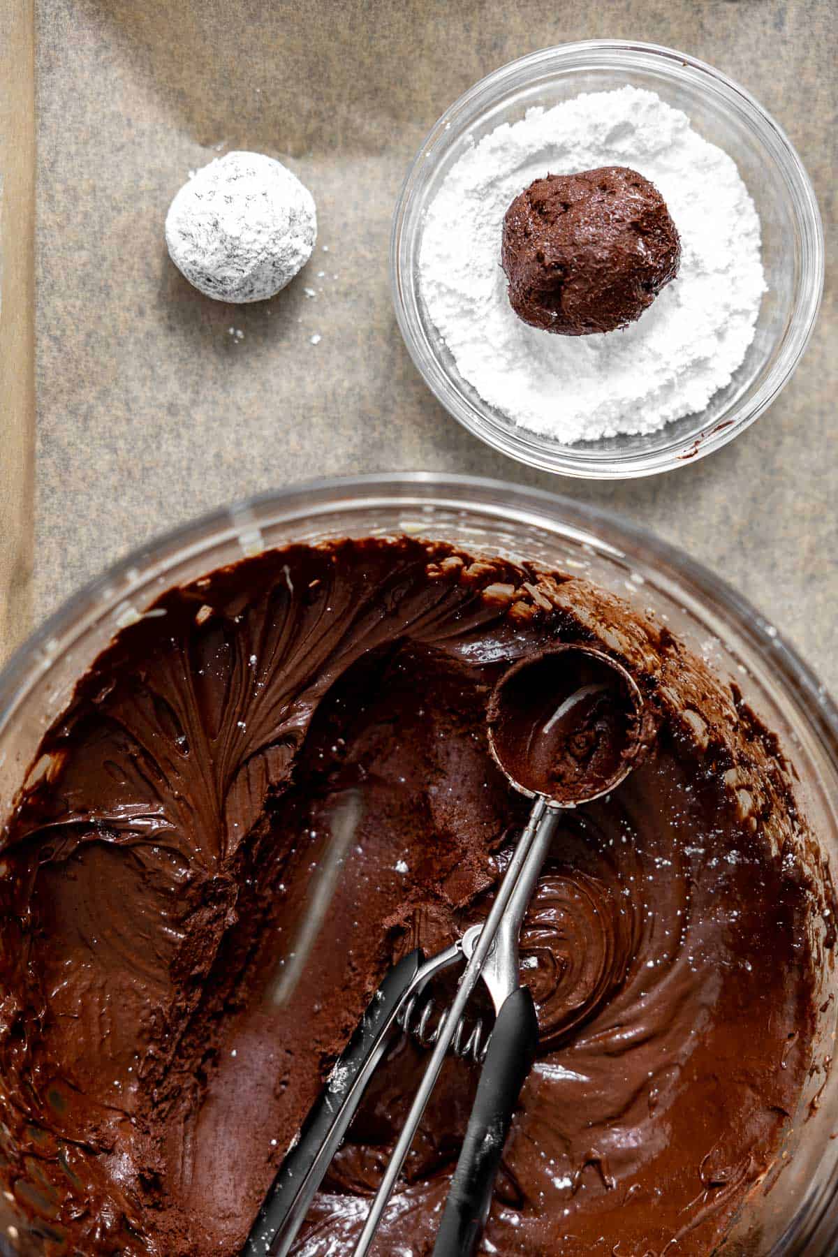 a cookie scoop in a bowl of flourless crinkle cookie dough.