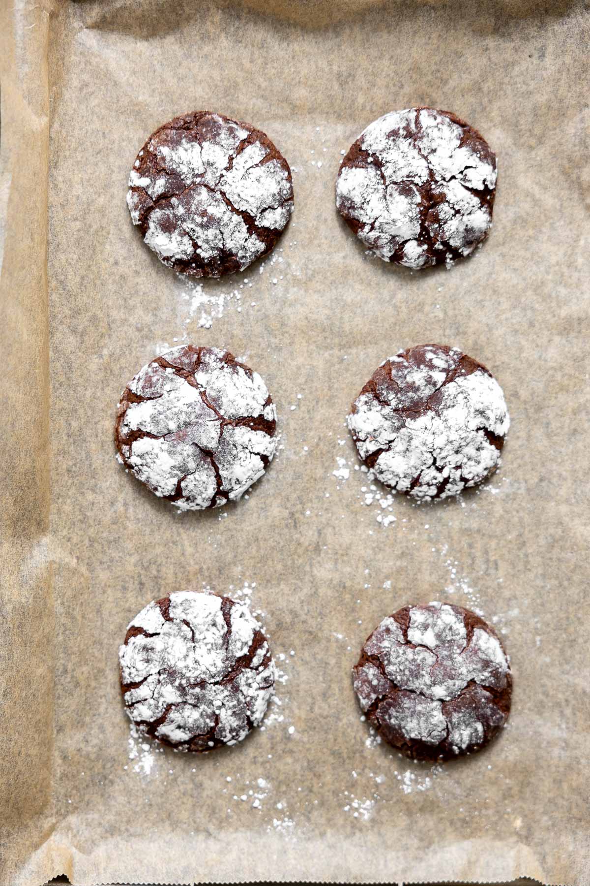 fresh baked gluten free crinkle cookies cooling on a baking sheet.