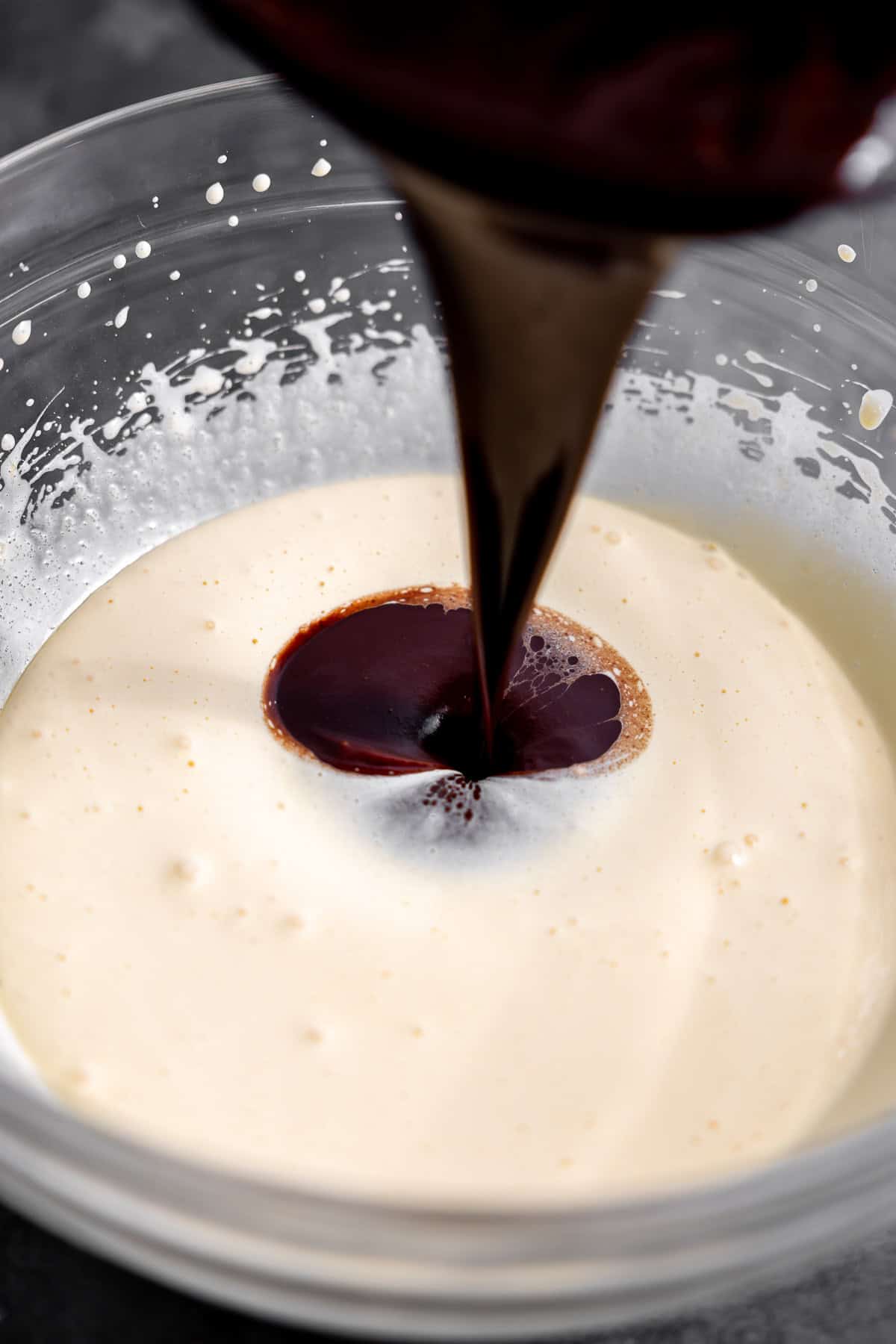 pouring melted chocolate and butter into beaten egg and sugar.