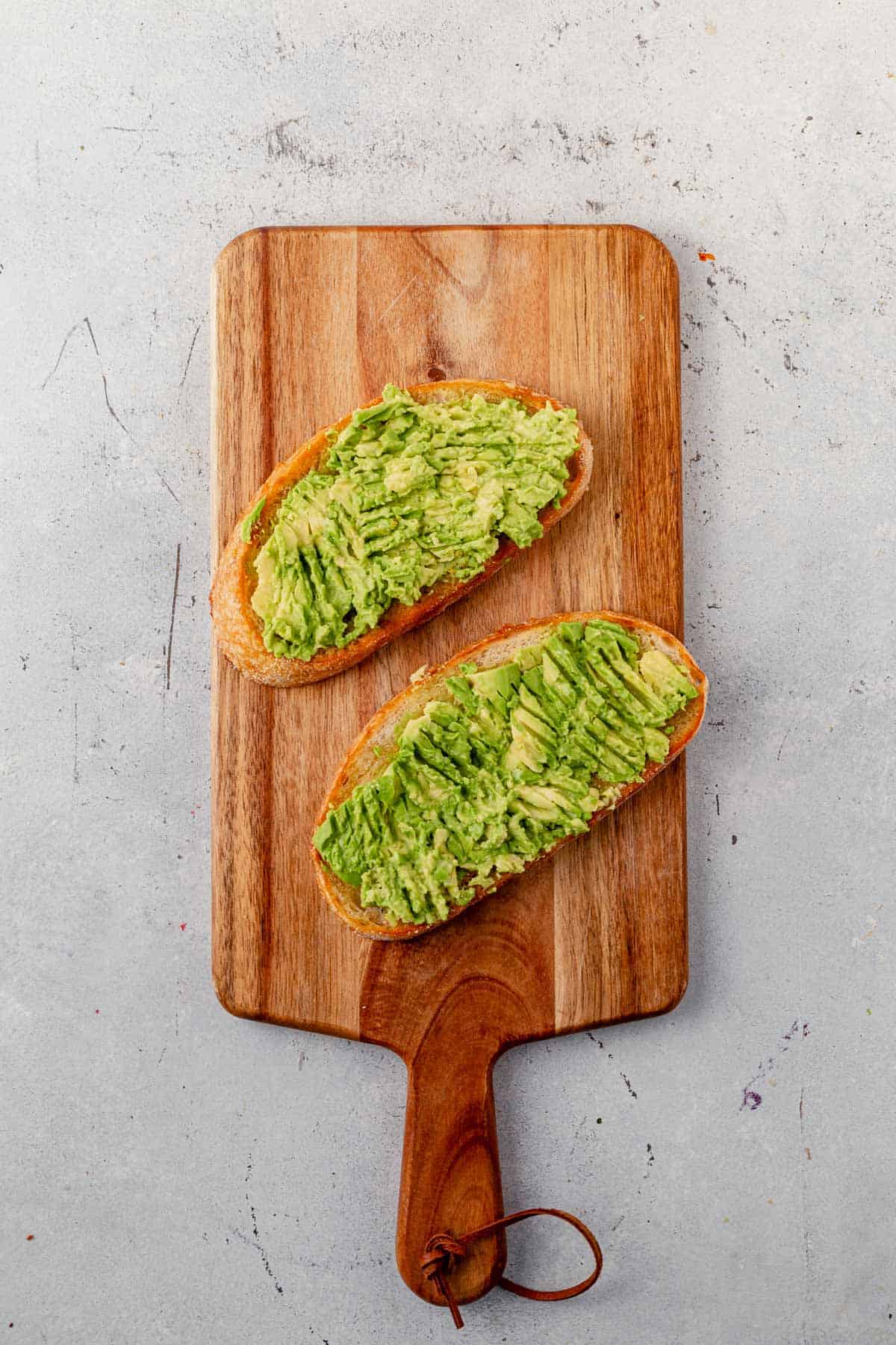 smashed avocado on two pieces of toasted bread.