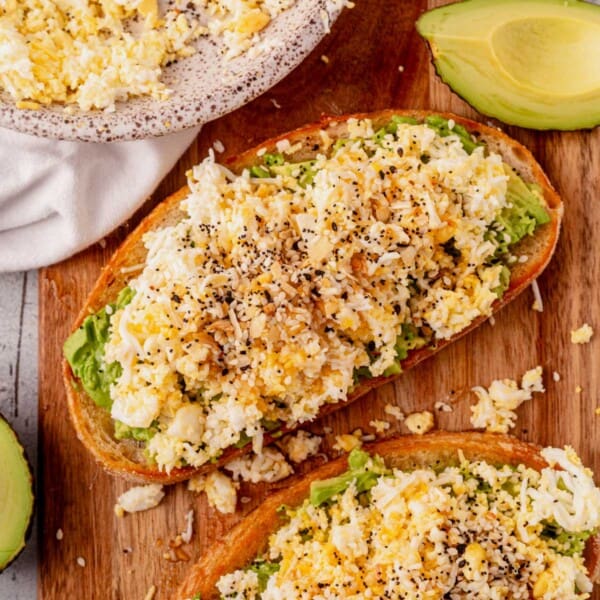 a slice of grated egg avocado toast on a cutting board.