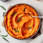 brown butter mashed sweet potatoes in a dish with a serving spoon.