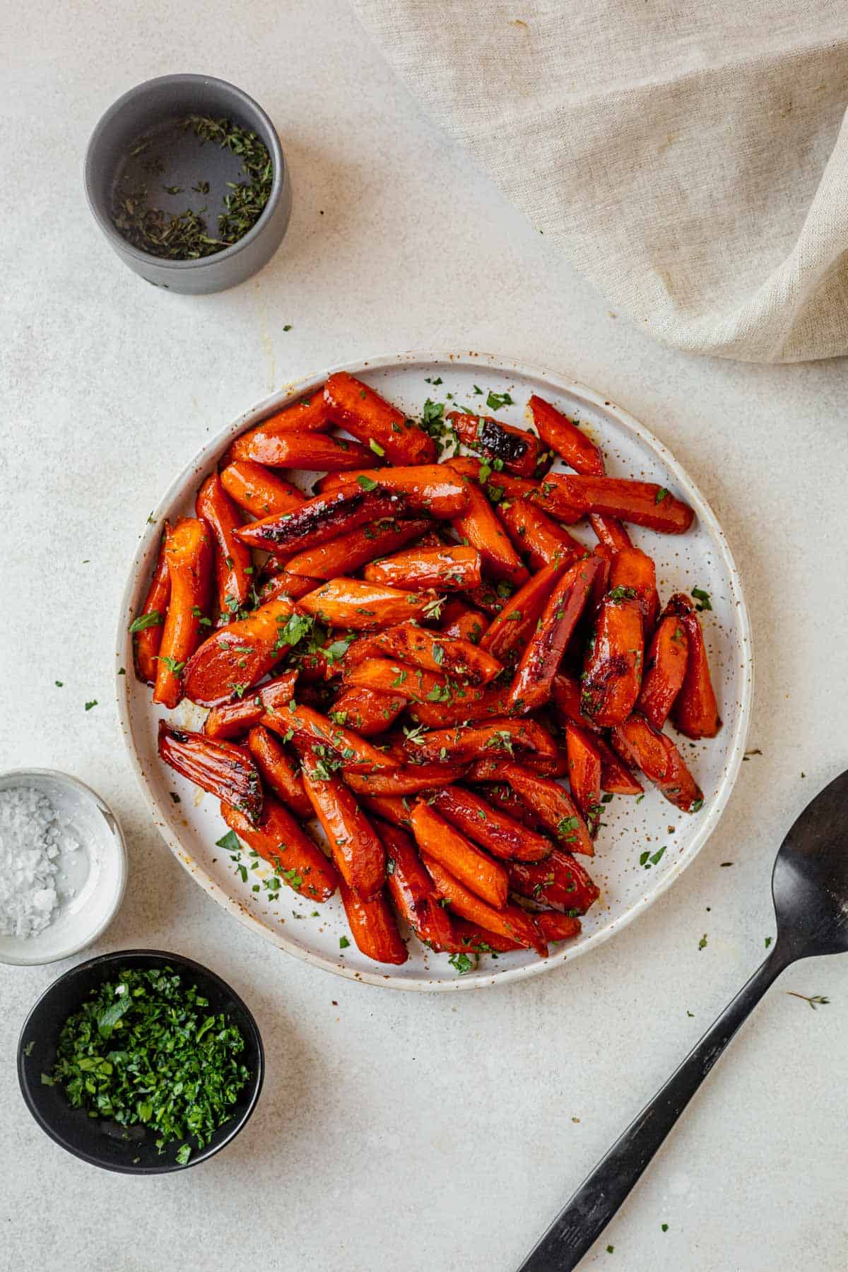 a plate of brown sugar carrots roasted in the oven topped with parsley.