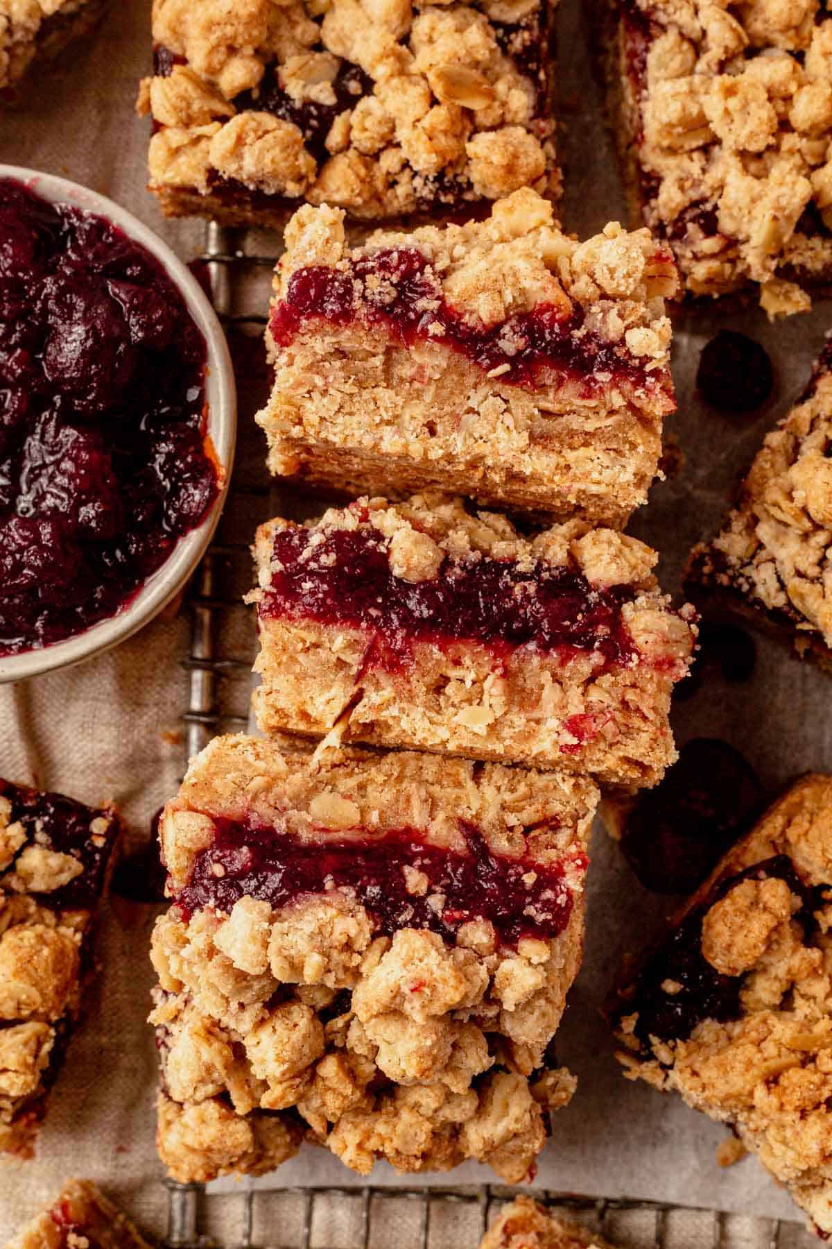 three cranberry oatmeal bars lying on their side showing a layer of cranberry inside.