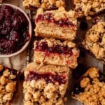 cranberry oatmeal bars on a cooling rack next to a bowl of cranberry sauce.