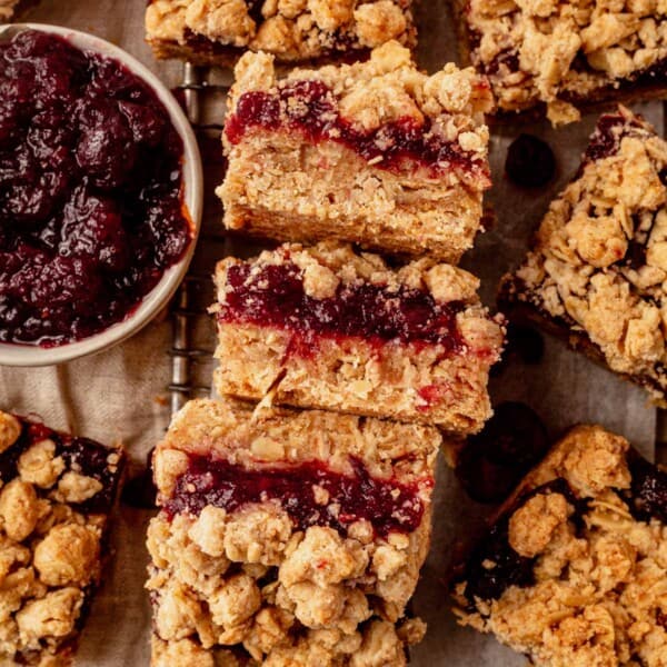 cranberry oatmeal bars on a cooling rack next to a bowl of cranberry sauce.