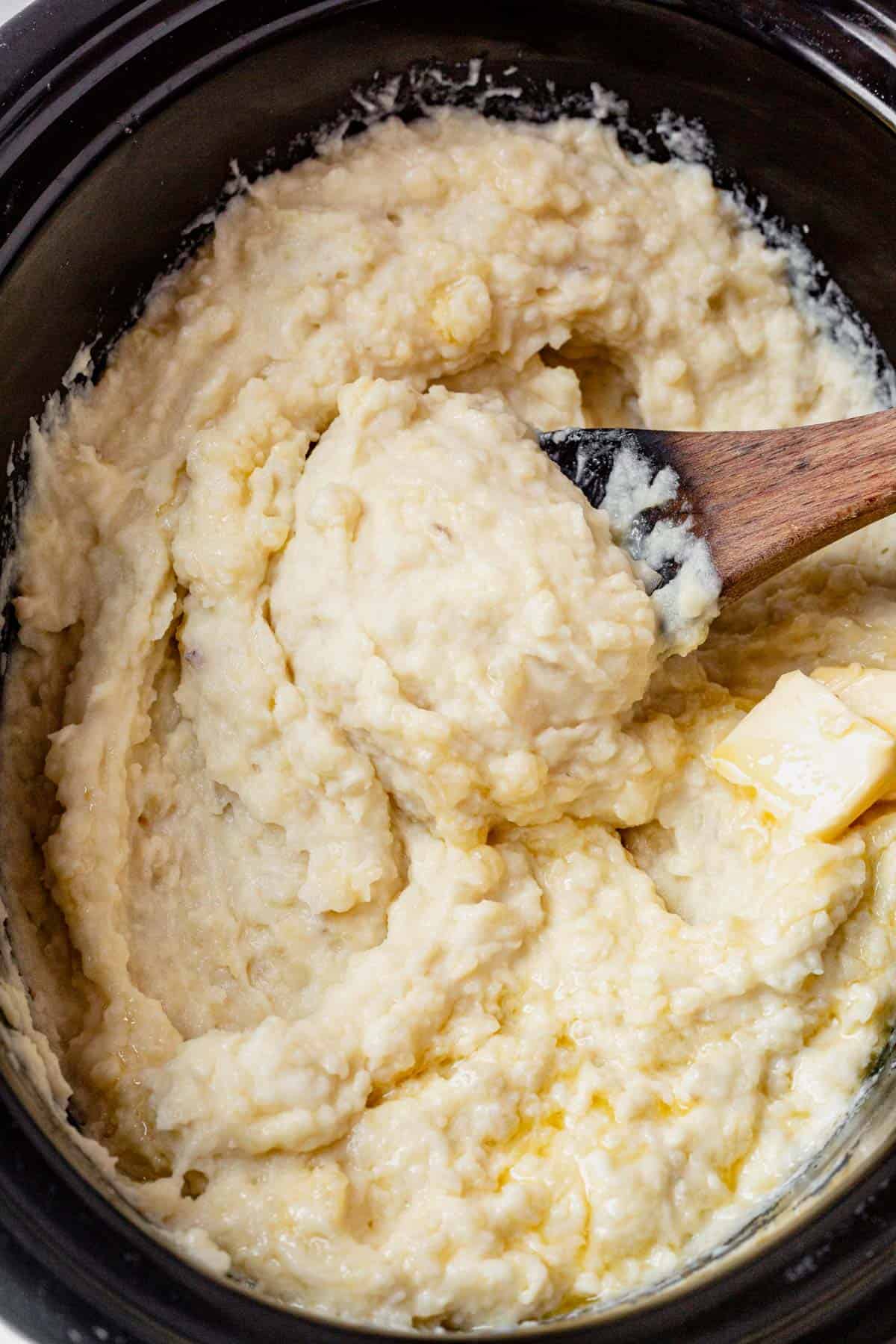 stirring mashed potatoes in the crock pot with a wooden spoon.