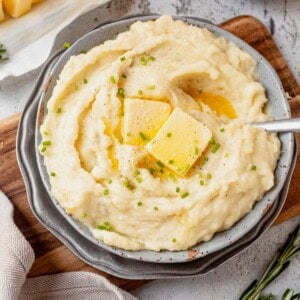 crock pot mashed potatoes in a bowl with butter and chives on top.