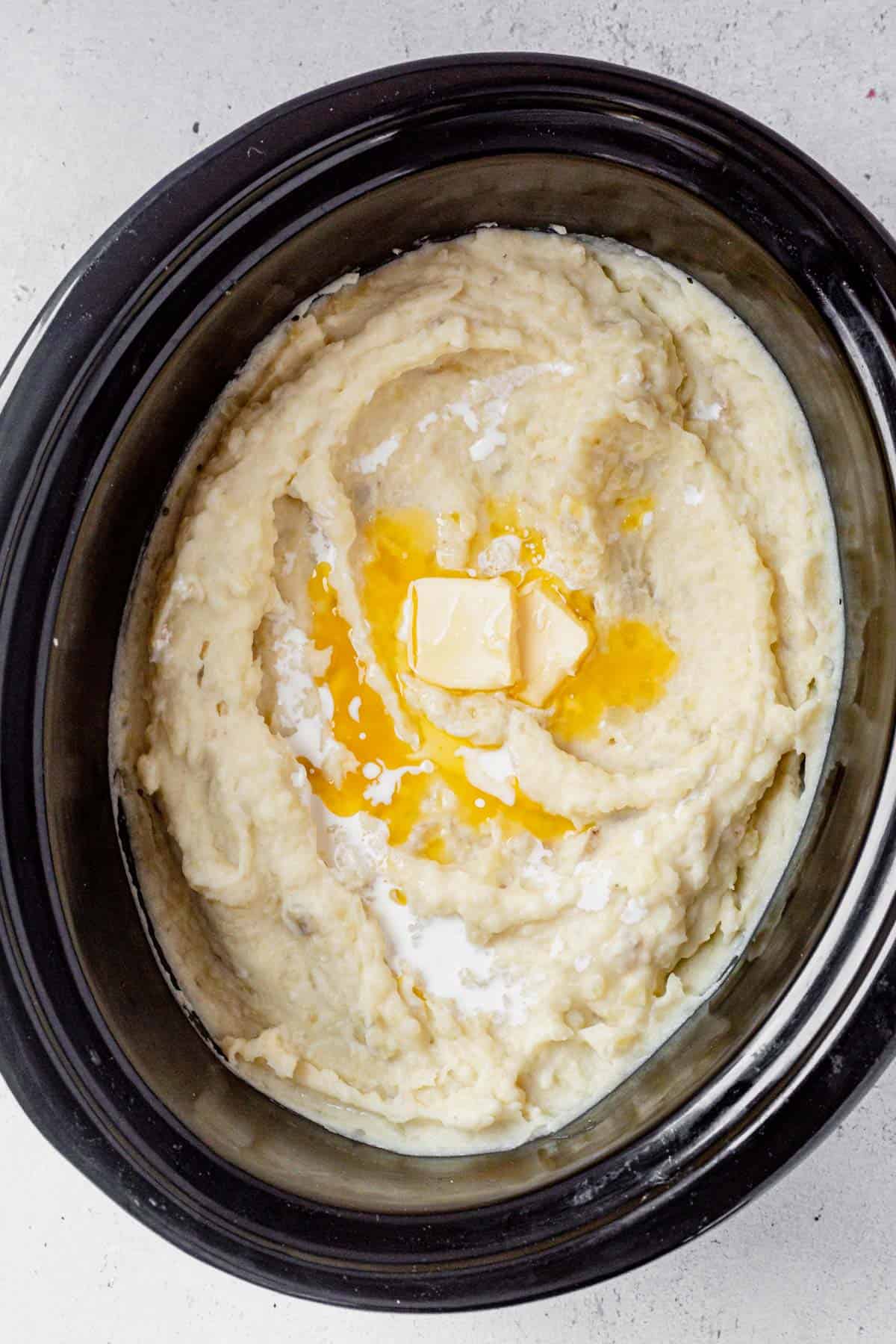 mashed potatoes in the crock pot with melted butter on top.