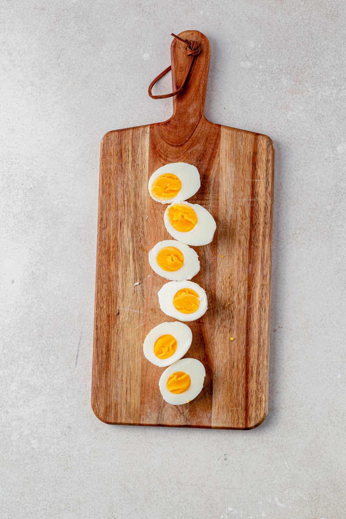 hard boiled eggs cut in half on a cutting board.