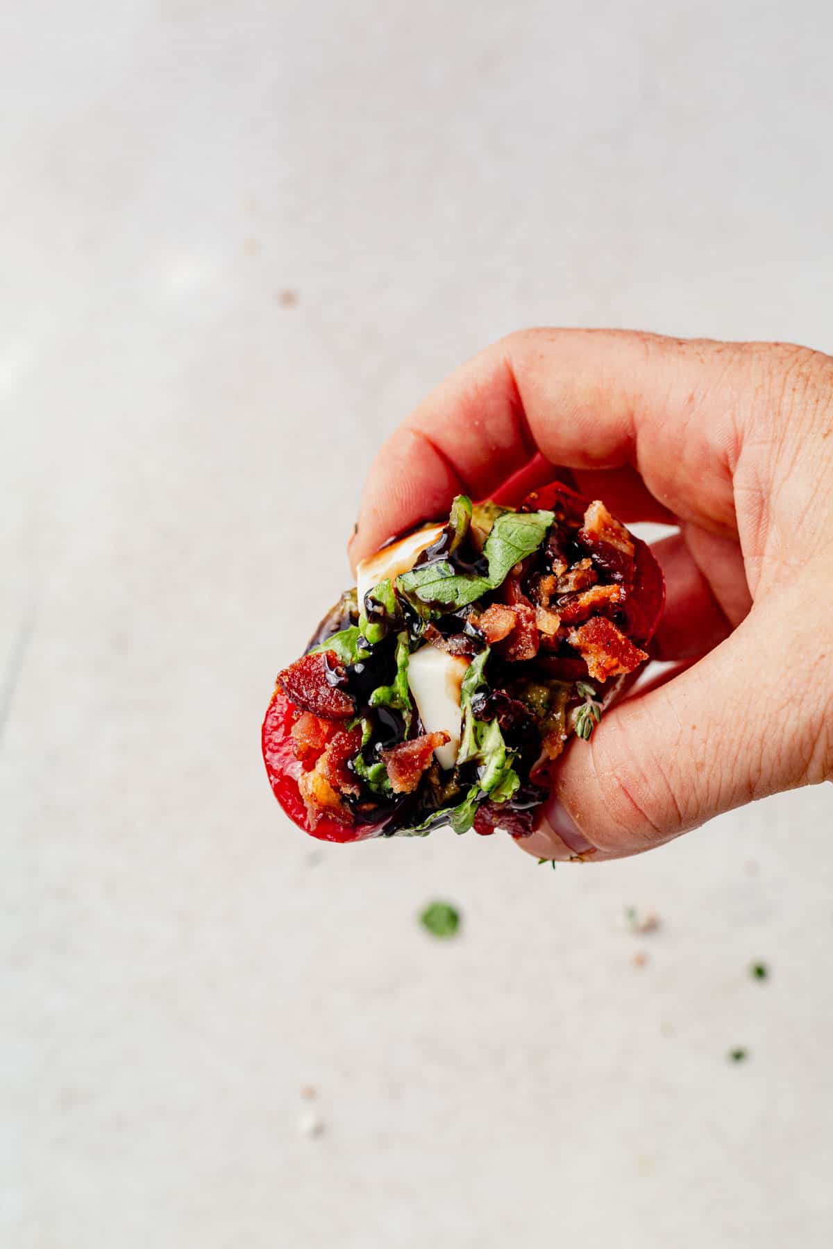 hand holding a pesto BLT hard boiled egg with balsamic glaze. 