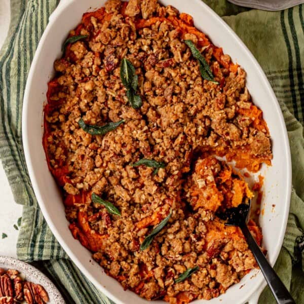 sweet potato casserole with pecan streusel topping with a serving spoon.