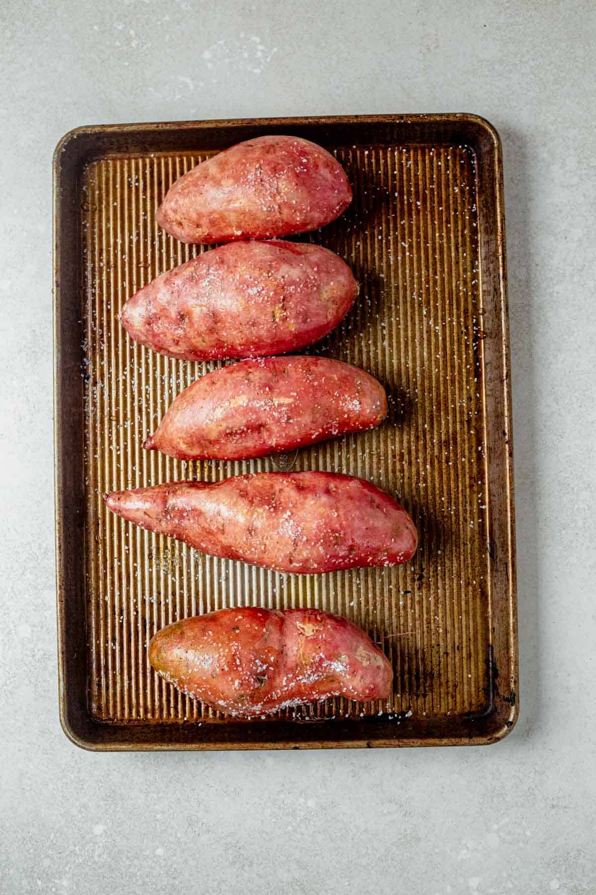 4 roasted sweet potatoes on a sheet pan.