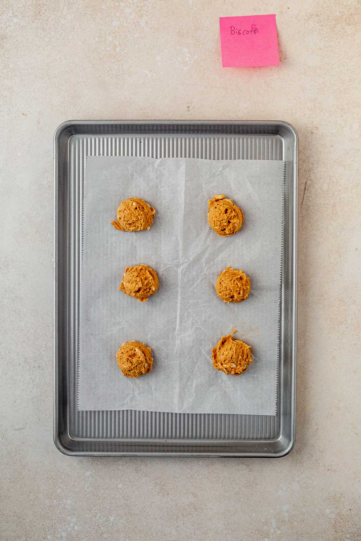 biscoff cookie dough balls on a parchment lined baking sheet.