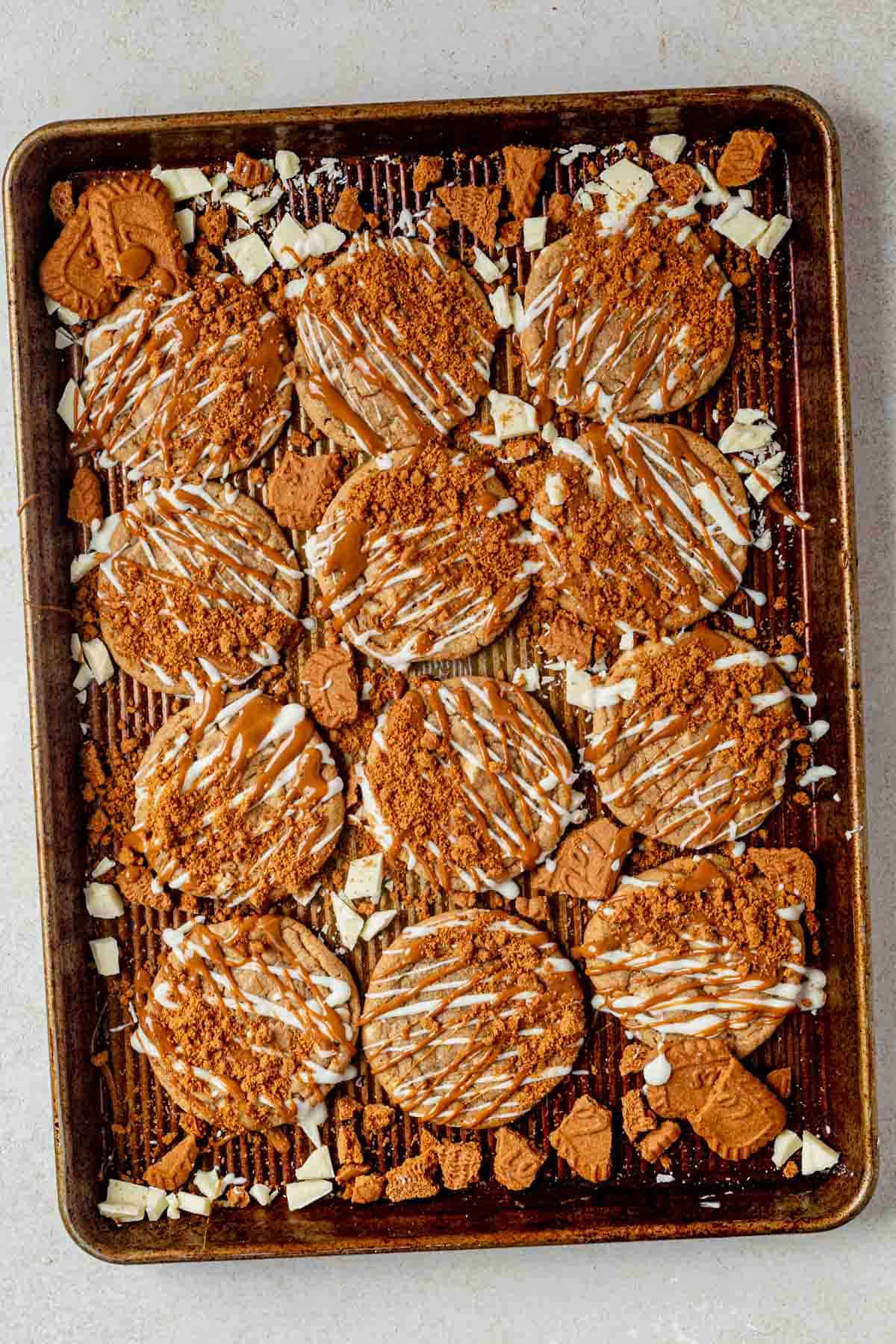 cookie butter cookies decorated with white chocolate drizzle and crushed biscoff cookies on a tray.