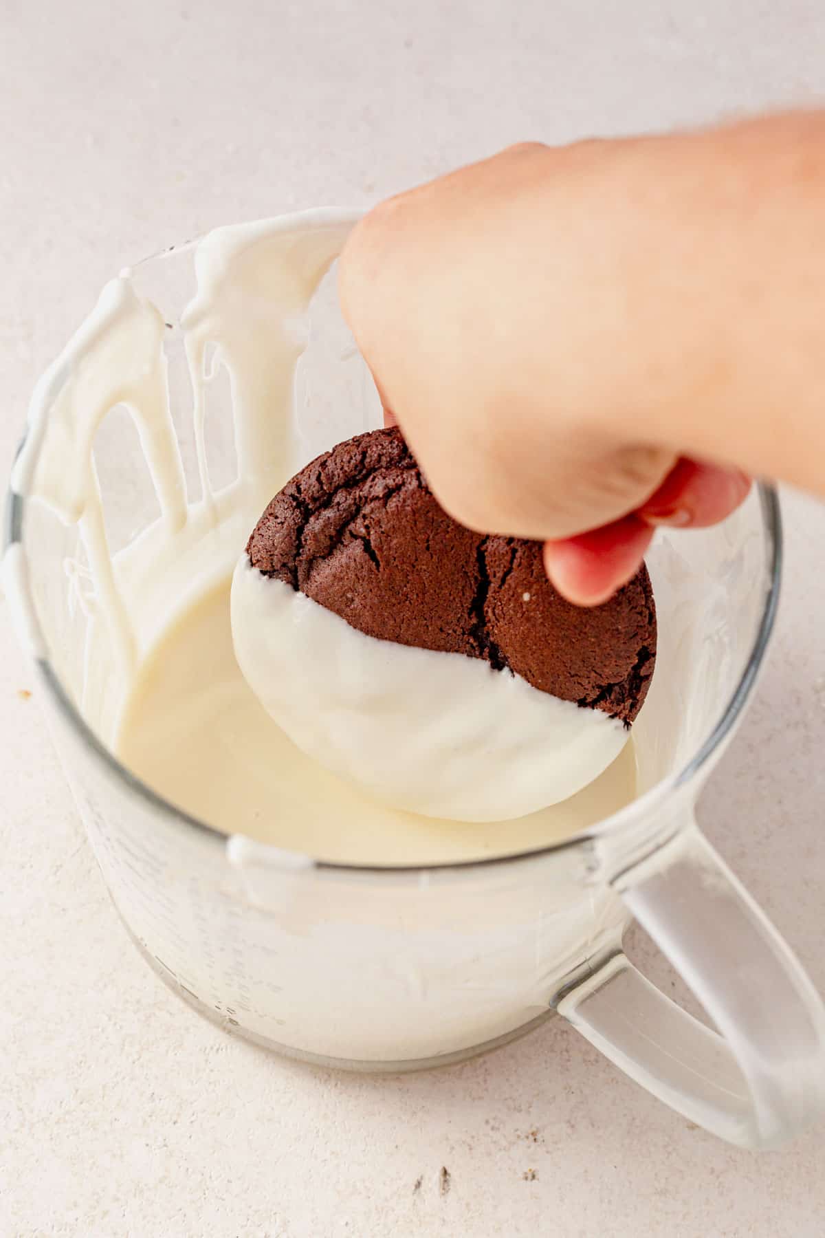 dipping an espresso martini cookie into melted white chocolate.