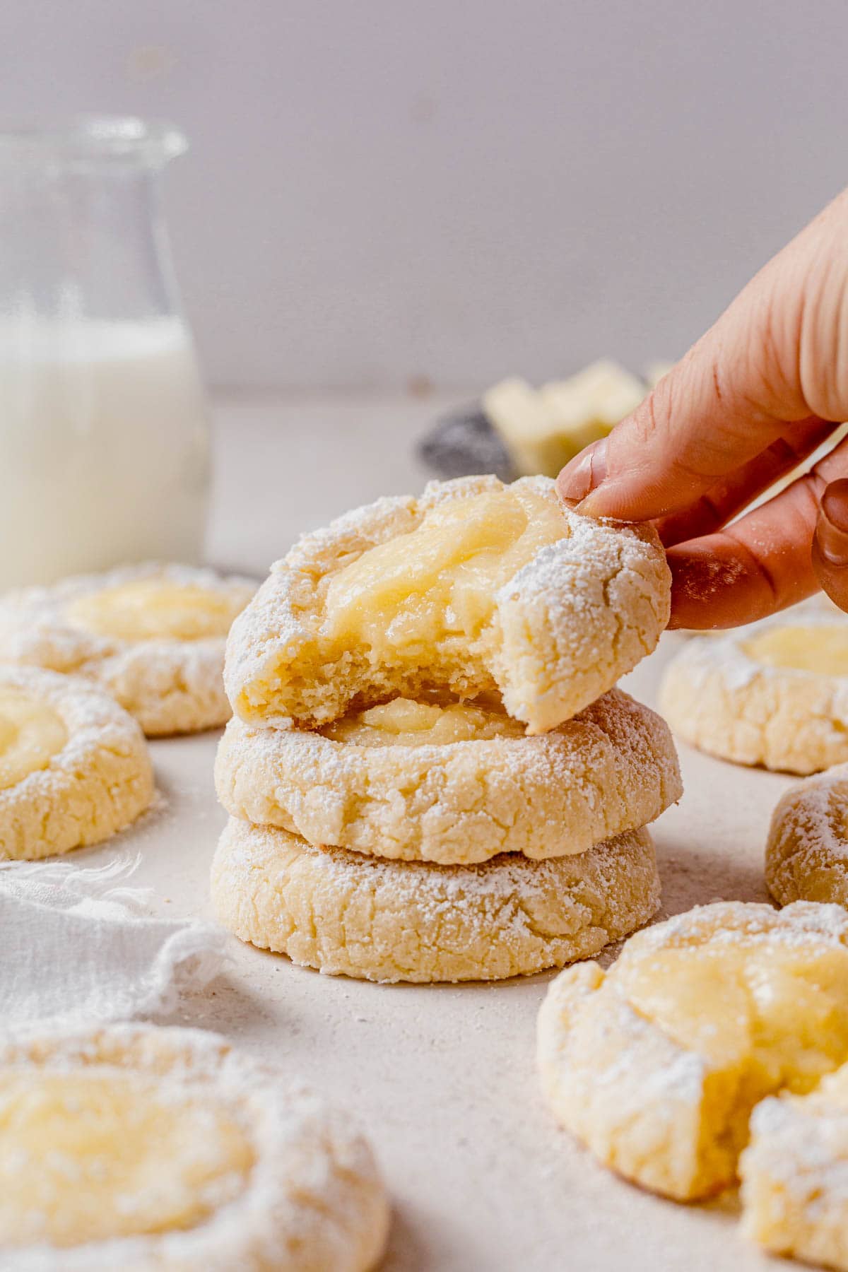 a stack of gooey butter cake cookies and a hand picking up the top one.