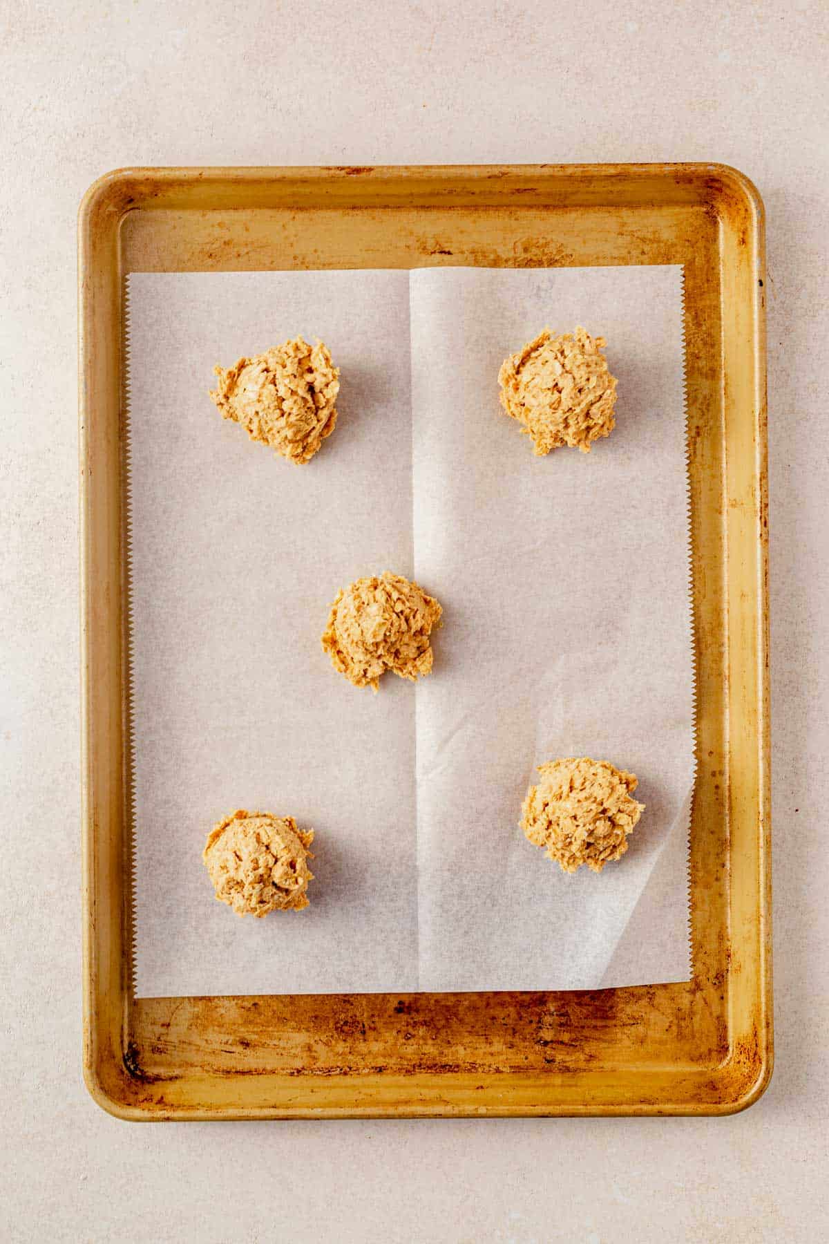 oatmeal cookie dough balls on a parchment lined baking sheet.