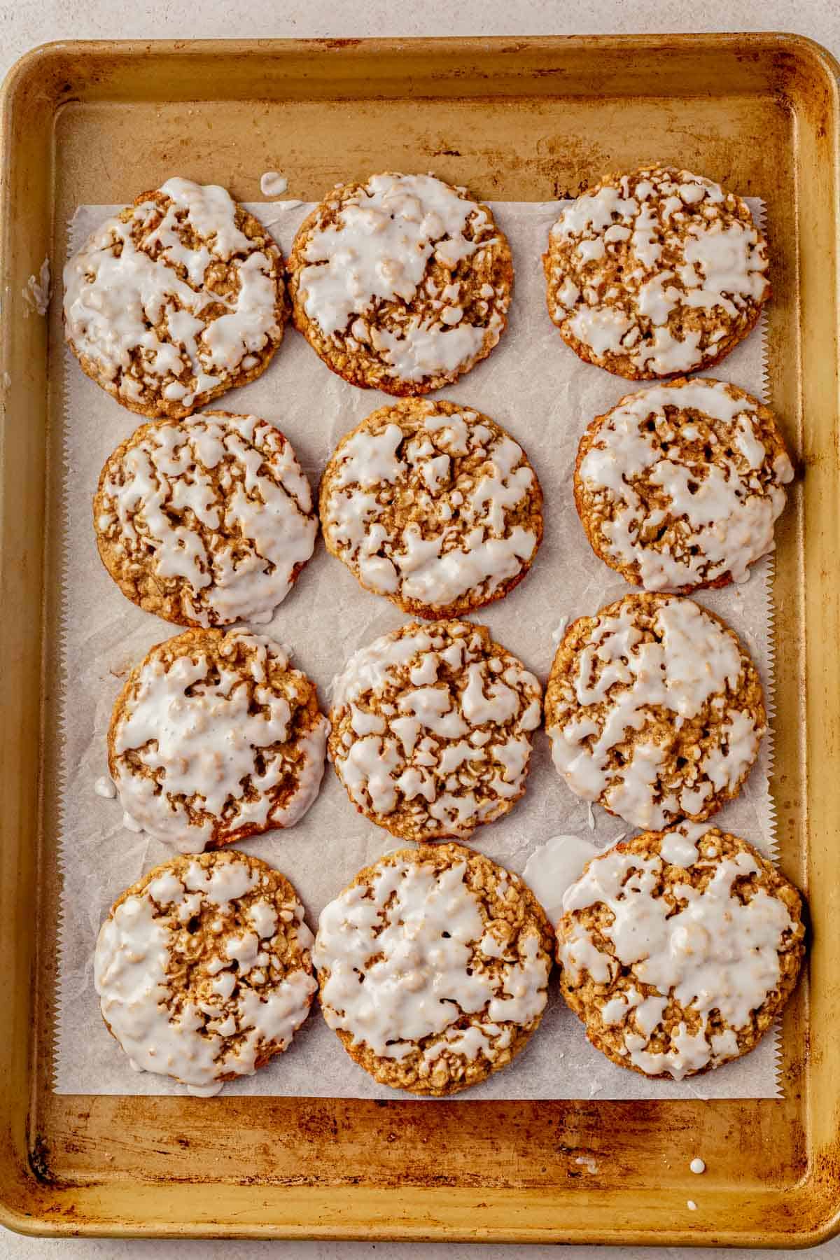 iced oatmeal cookies setting on a cookie sheet.