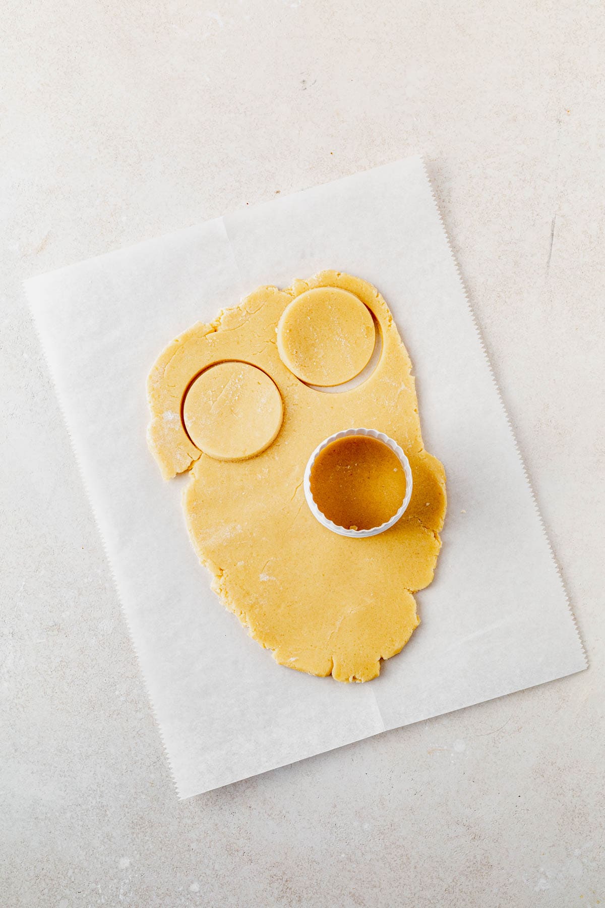 shortbread cookie dough rolled out on a counter with a circle cookie cutter on top.