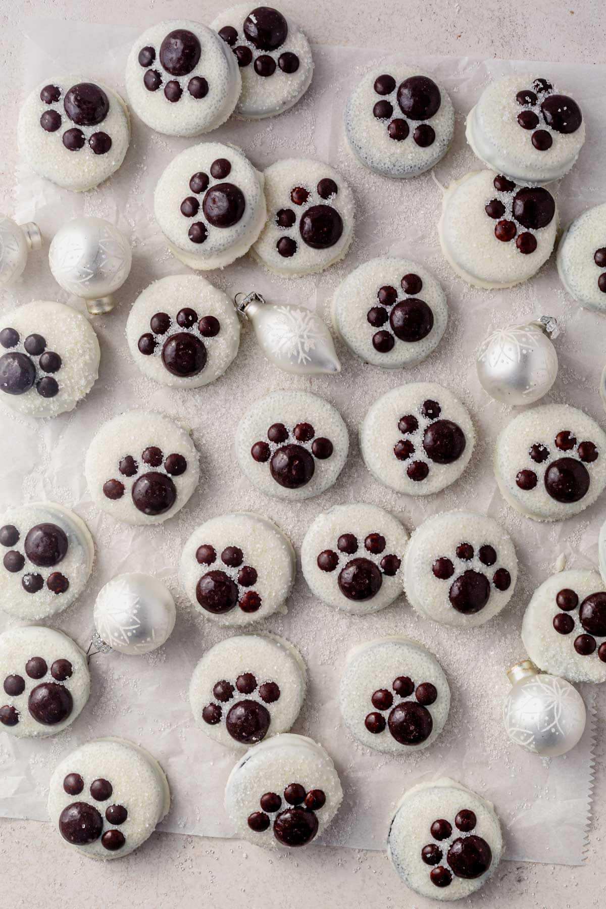 polar bear paw oreos on a counter with sanding sugar and christmas ornaments.