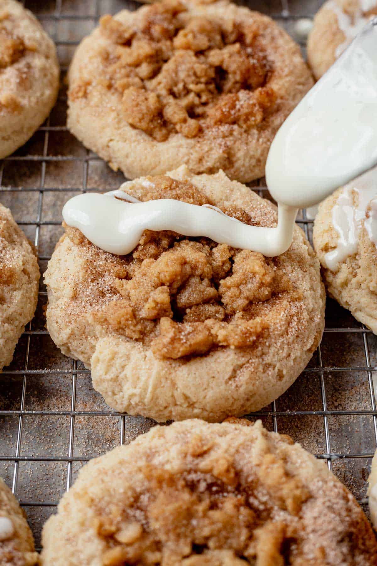 drizzling icing over coffee cake cookies on a cooling rack.