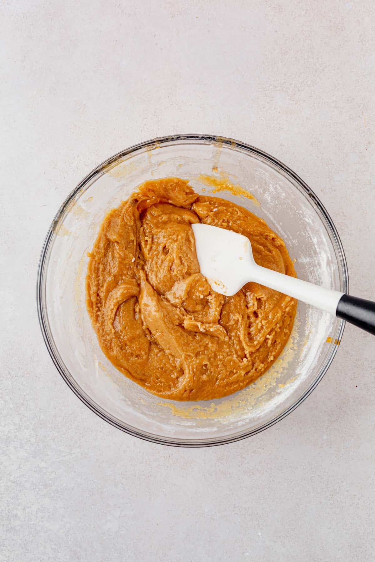 brown butter cookies dough in a mixing bowl with a rubber spatula.