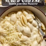 fork in a bowl of white cheddar mac and cheese sprinkled with shredded white cheddar.