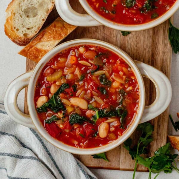 a bowl of blue zone minestrone soup with crusty bread on the side.