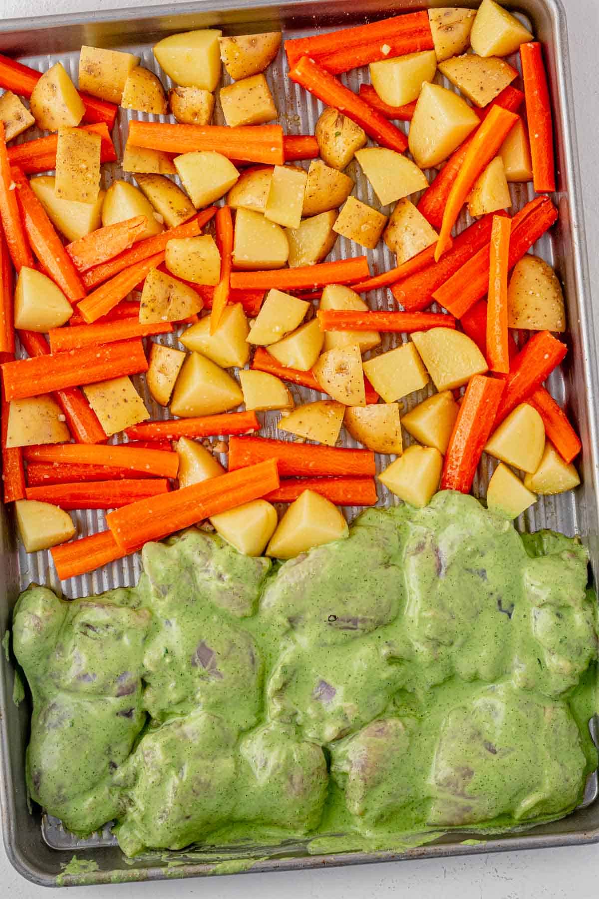 green goddess marinated chicken on a sheet pan with potatoes and carrots.