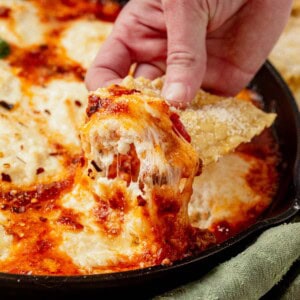 scooping lasagna dip out of a skillet.