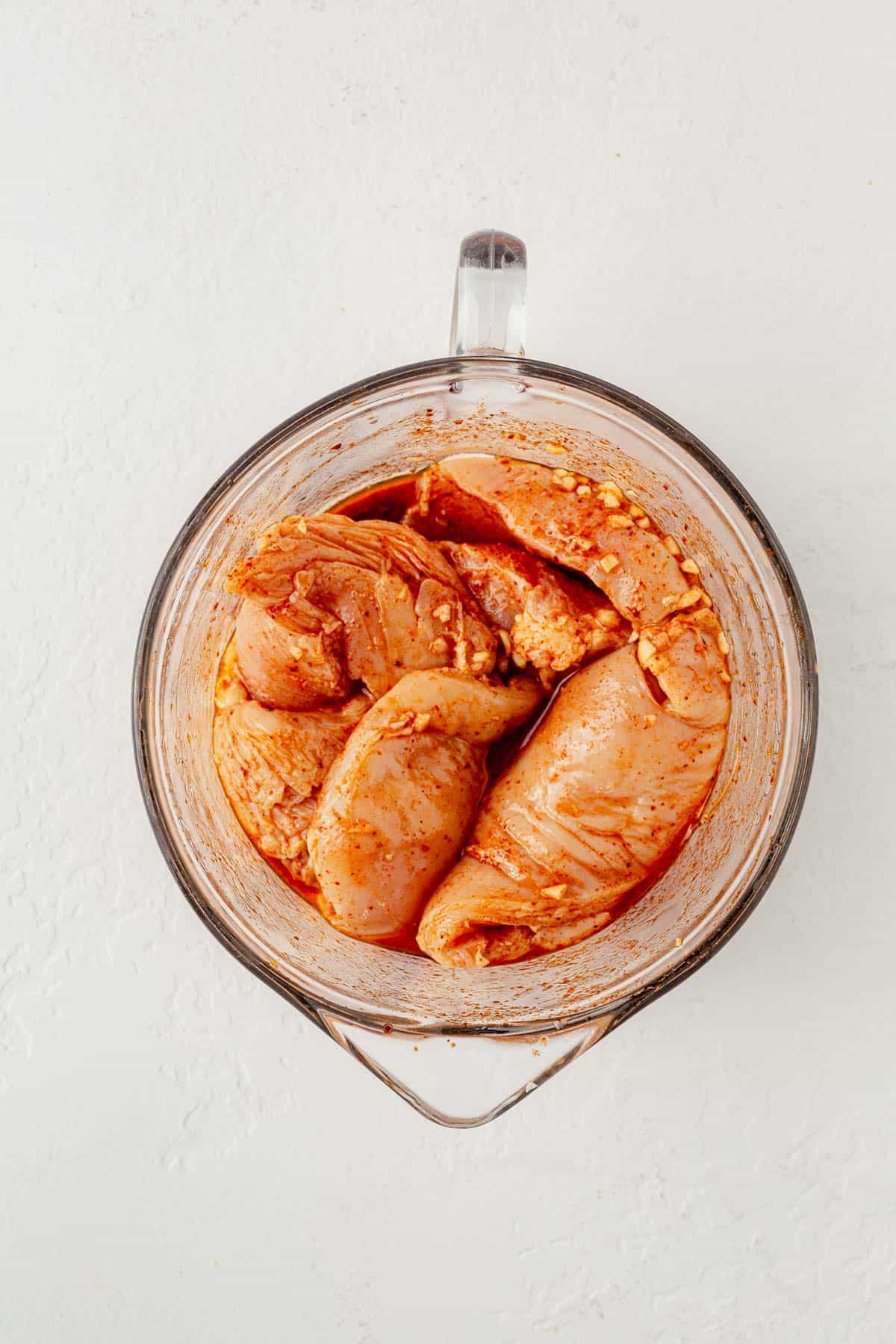 marinated chicken breasts in mexican seasoning in a glass bowl.