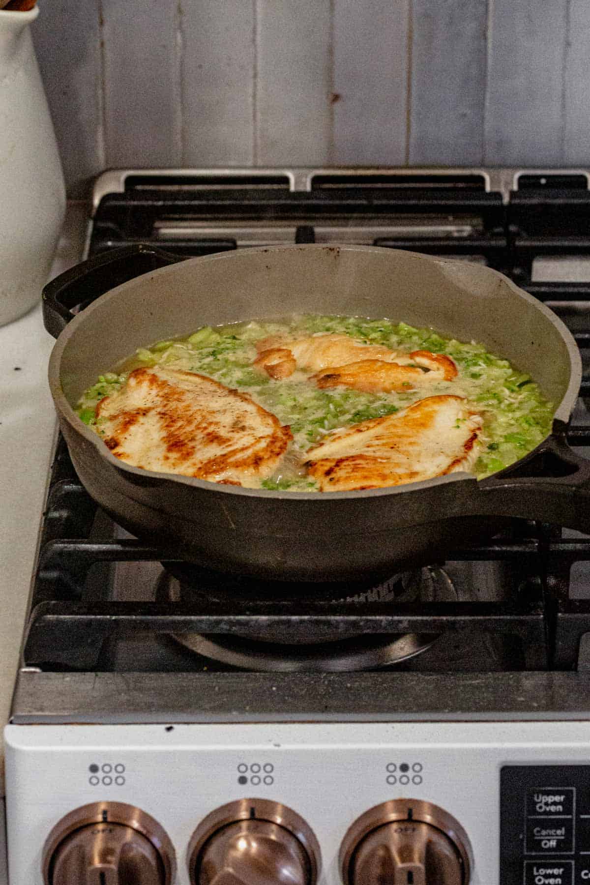 cooking broccoli, rice, and chicken on the stove in a skillet.