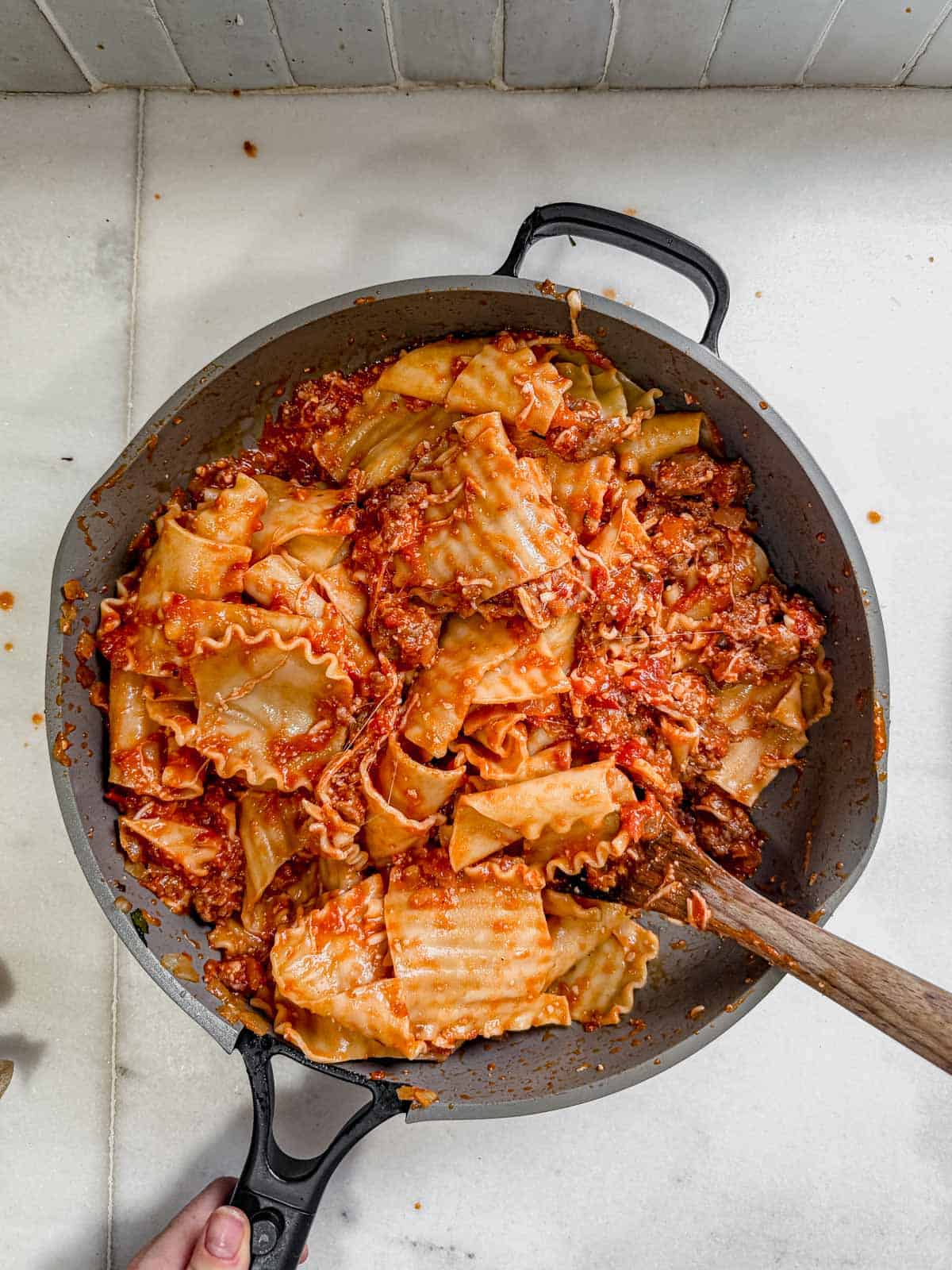 lasagna noodles mixed with meat sauce in a skillet.