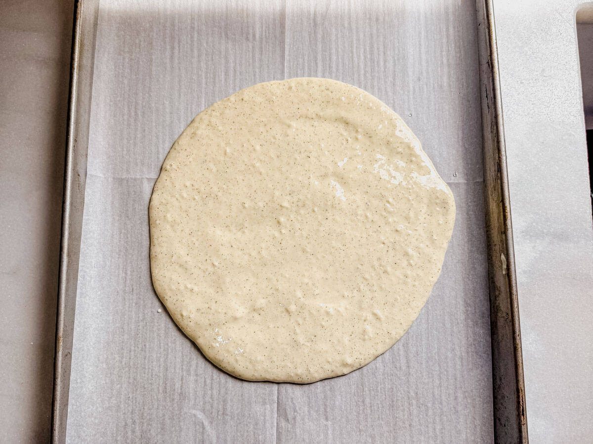 cottage cheese pizza crust spread out onto a baking pan.