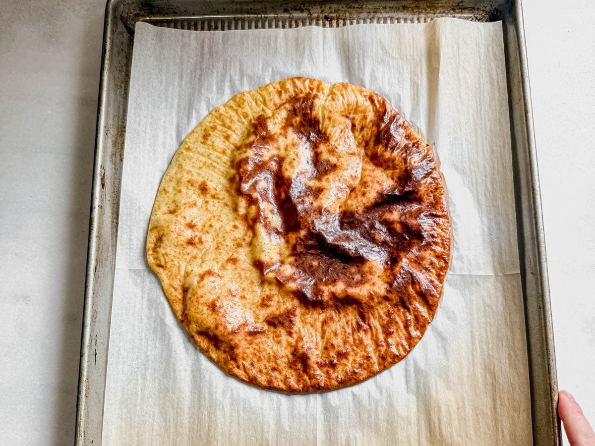 baked golden brown cottage cheese pizza crust cooling on a baking sheet.