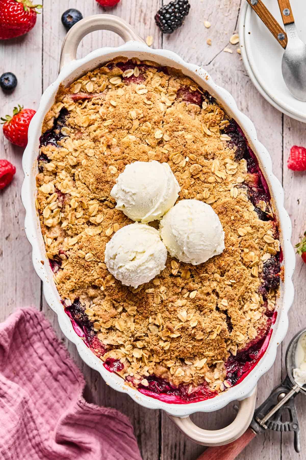 baked gluten free berry crisp with two scoops of vanilla ice cream on top