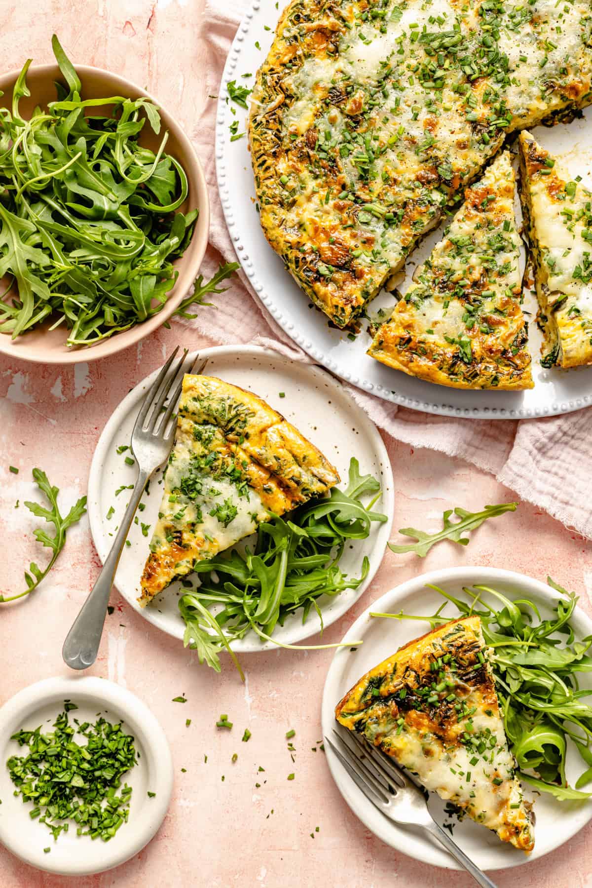 vegetable frittata slices served on plates with fresh arugula