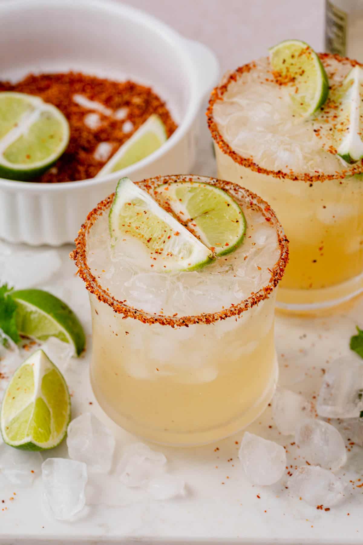 hot honey margarita with tajin rim topped with lime wedges