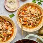 low-carb turkey soup in two bowls on a table with a small bowl of parmesan cheese and a dutch oven
