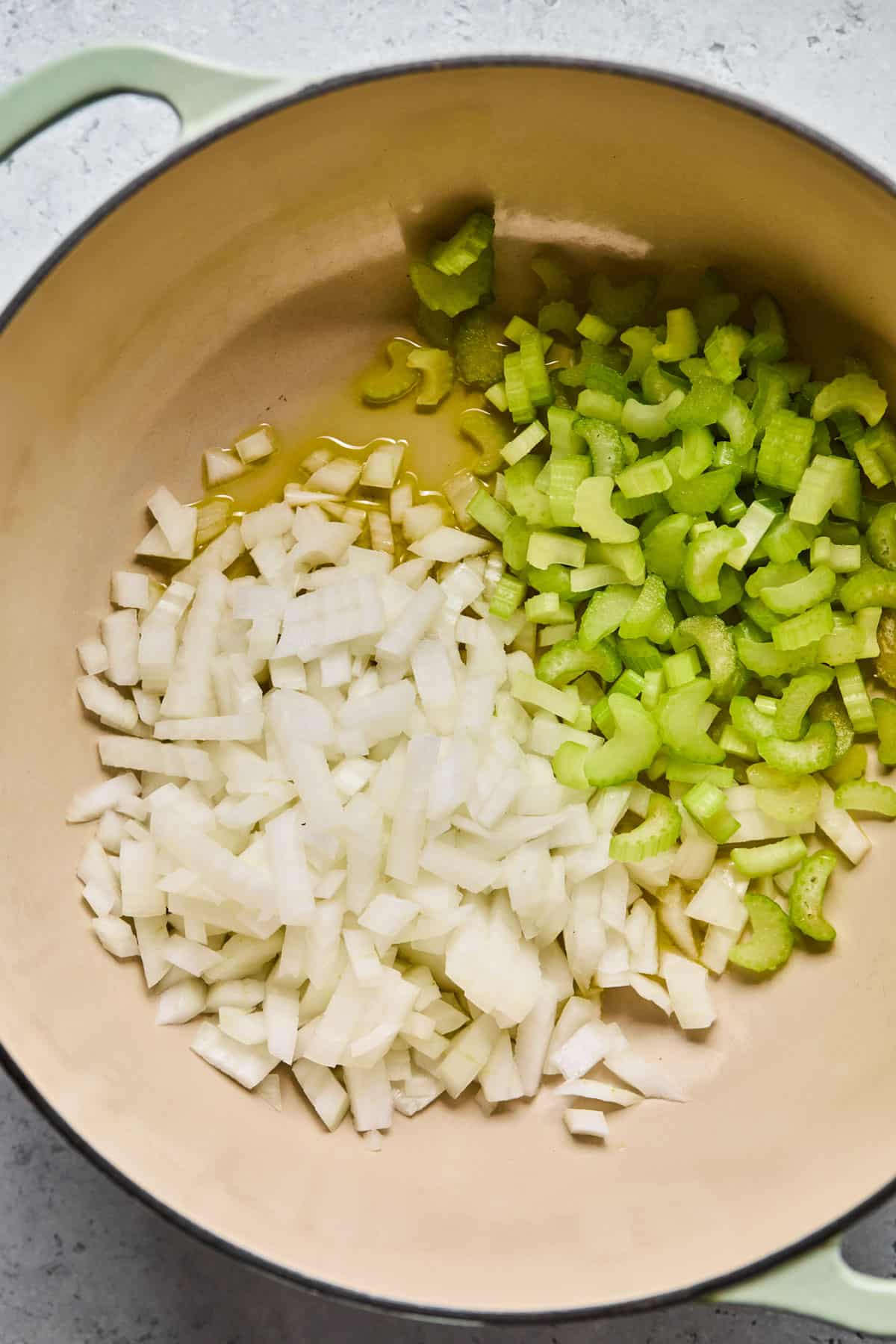 onions and celery chopped up and being sauteed in a dutch oven