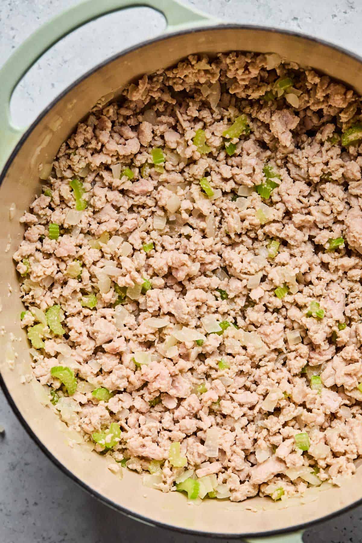 ground turkey browning in a dutch oven with sauteed onions, garlic, and celery